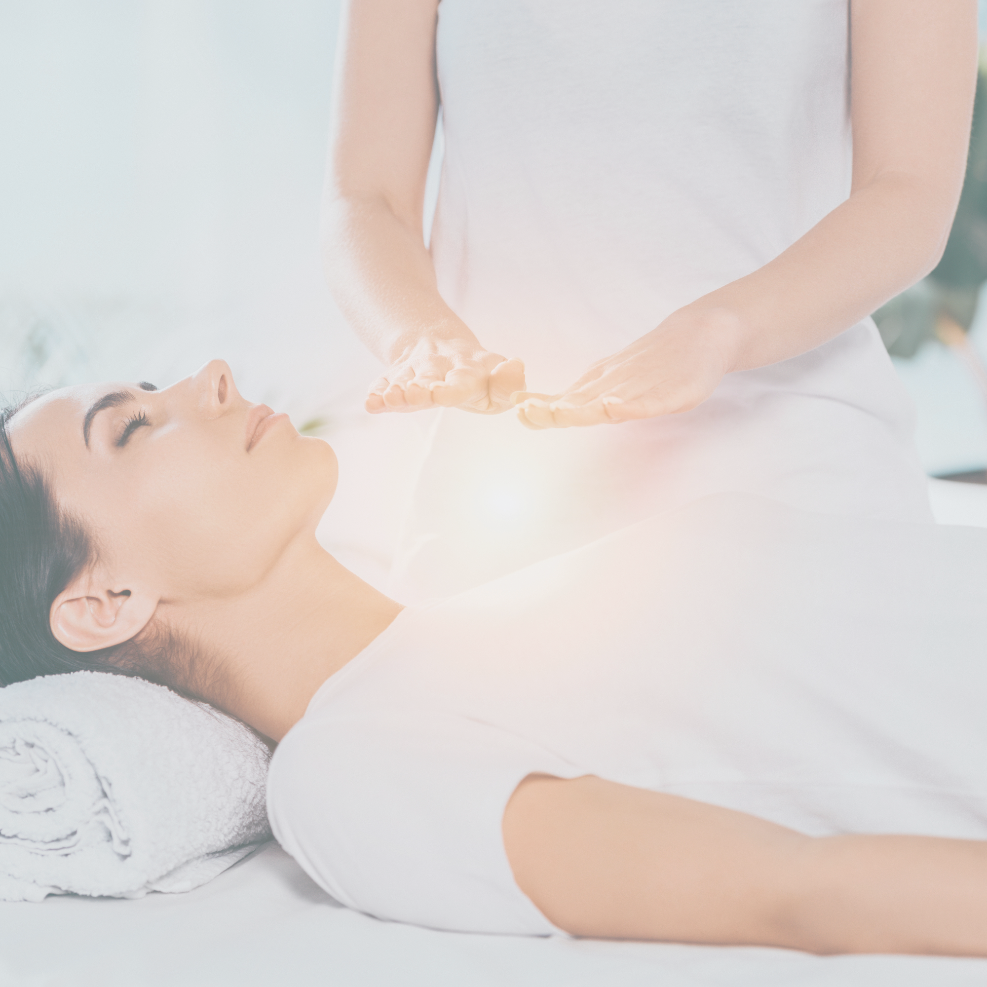 woman lying on massage table receiving Reiki above her heart space